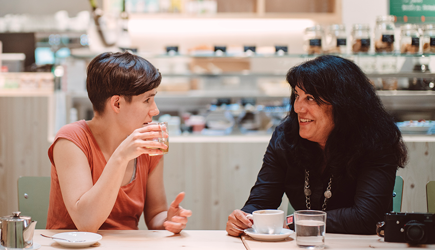 Two women chat over coffee at a cafe. We can clear up a lot of myths about living with UI by talking about them more.