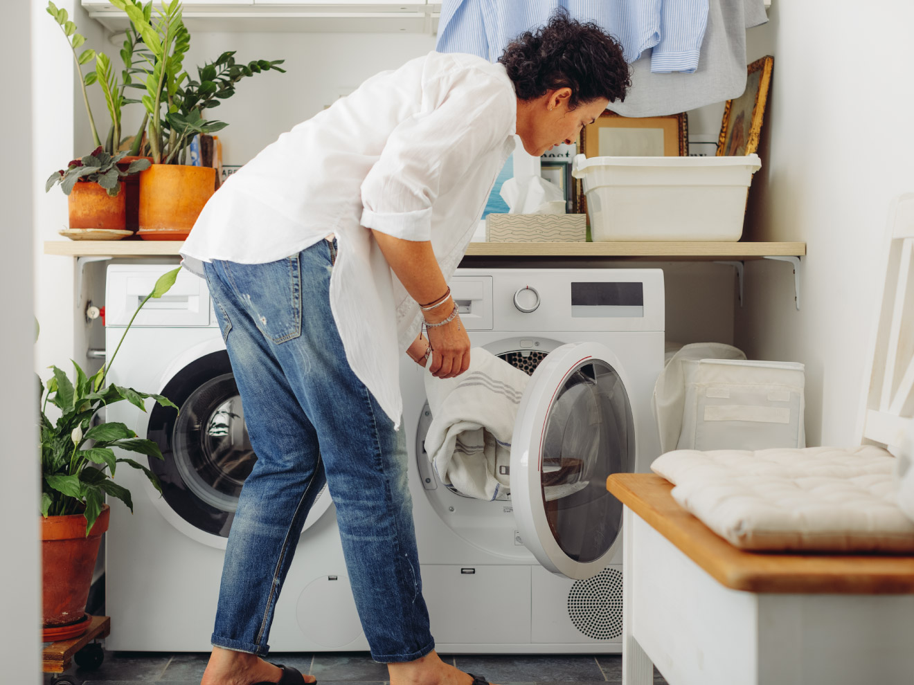A woman puts a load of laundry in the washing machine. Adding baking soda helps her clothes come out clean and fresh!